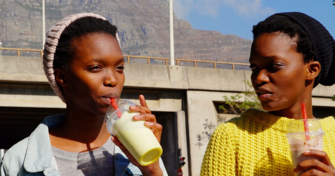 Twin Sisters Enjoying Smoothies Outdoors