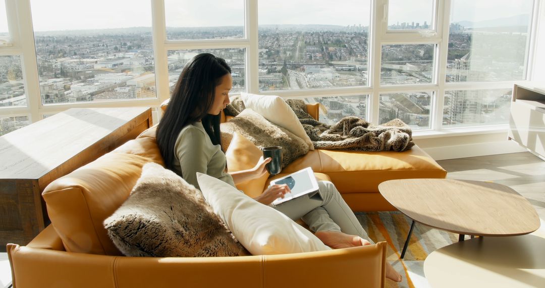 Woman Relaxing with Book and Coffee in Modern Apartment with City View - Free Images, Stock Photos and Pictures on Pikwizard.com