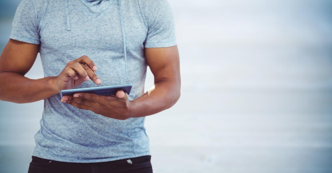 Man Using Tablet in Casual T-Shirt Against Blurry Blue Background - Free Images, Stock Photos and Pictures on Pikwizard.com