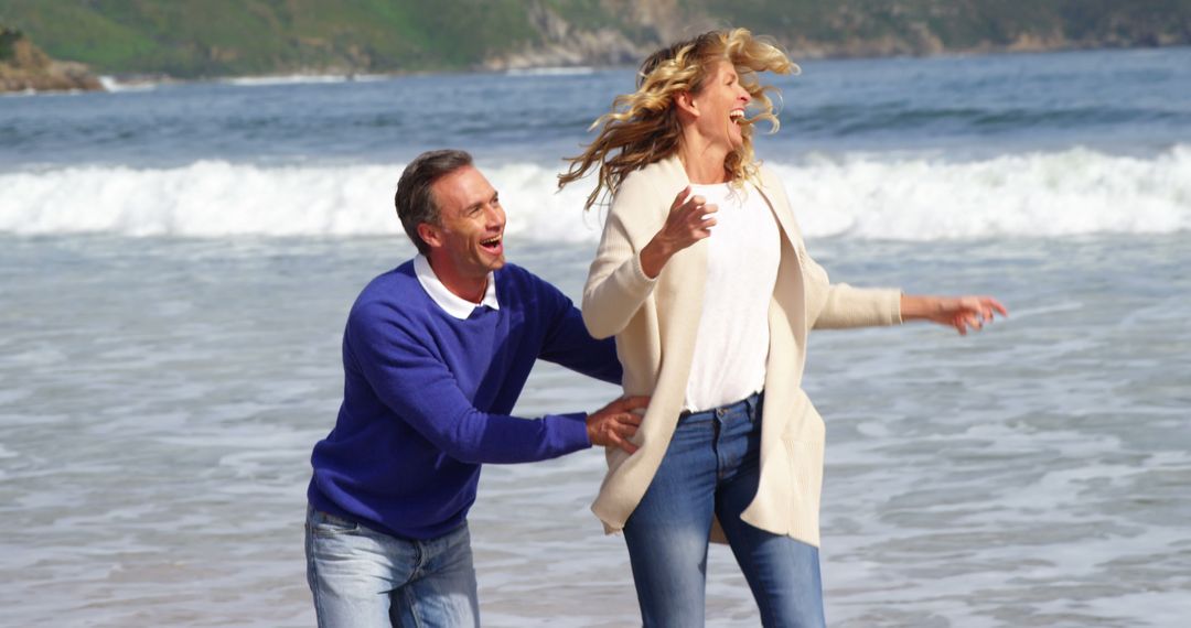 Happy Mature Couple Laughing and Playing at the Beach - Free Images, Stock Photos and Pictures on Pikwizard.com