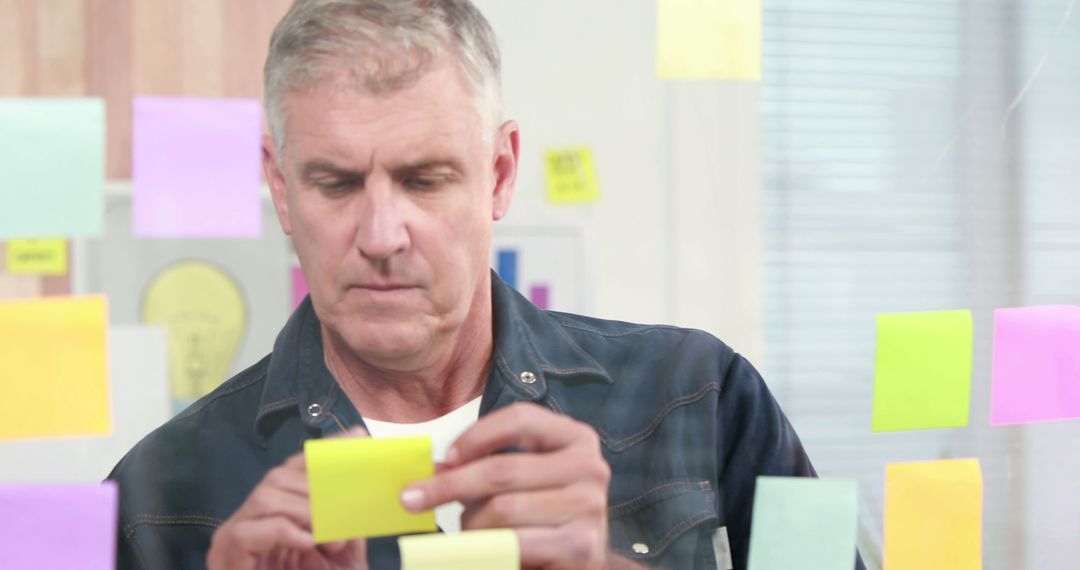 Focused Professional Analyzing Sticky Notes in Office