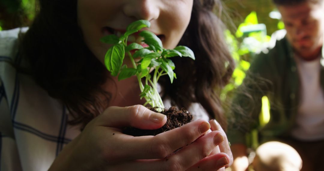 A young Caucasian girl gently smells a small plant she's holding, with copy space - Free Images, Stock Photos and Pictures on Pikwizard.com