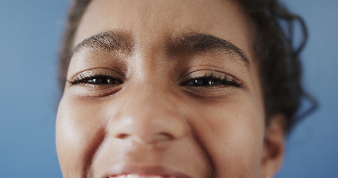 Close-up of African American Child Smiling Against Blue Background - Free Images, Stock Photos and Pictures on Pikwizard.com