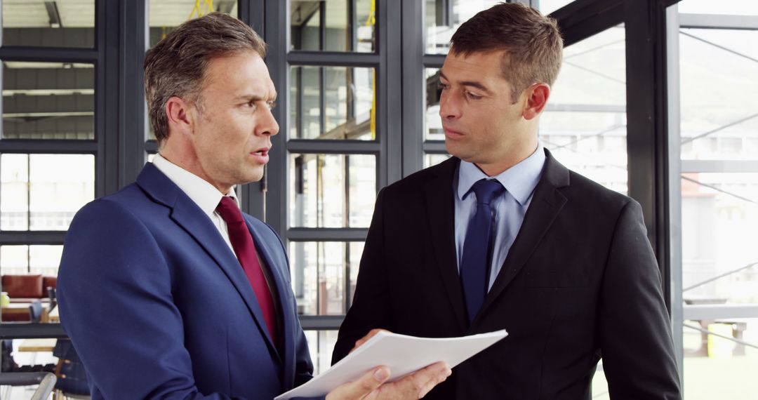 Two Businessmen Strategizing in Modern Office with Documents
