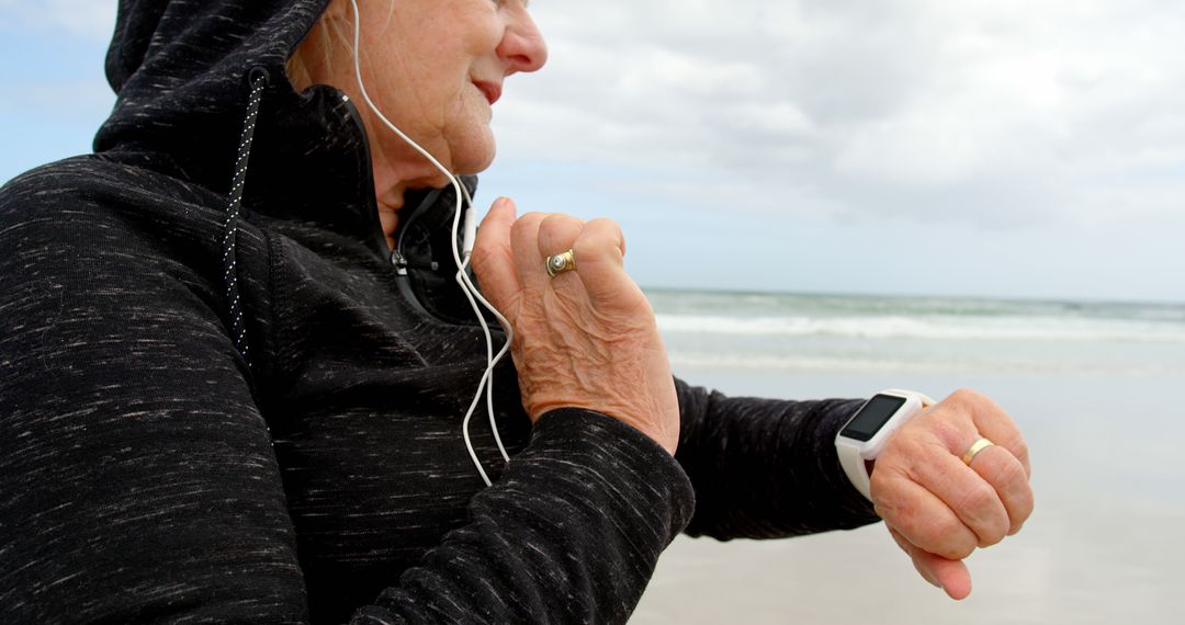 Senior Woman Exercising on Beach with Smartwatch and Earphones - Free Images, Stock Photos and Pictures on Pikwizard.com