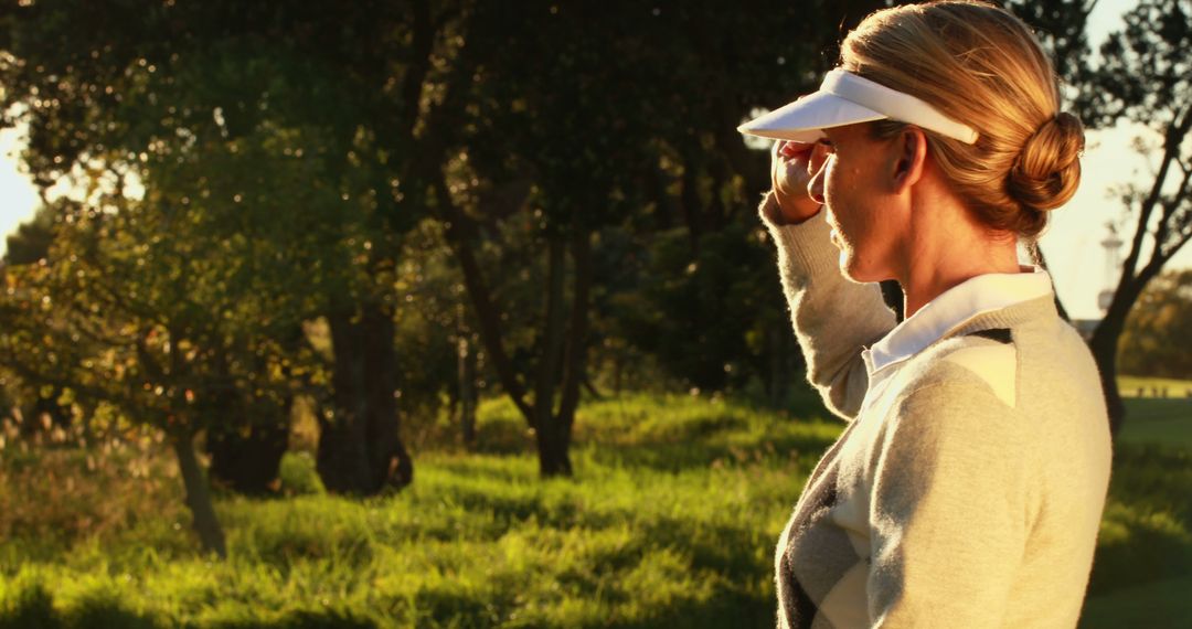 Woman shielding eyes in sunny park with visor - Free Images, Stock Photos and Pictures on Pikwizard.com