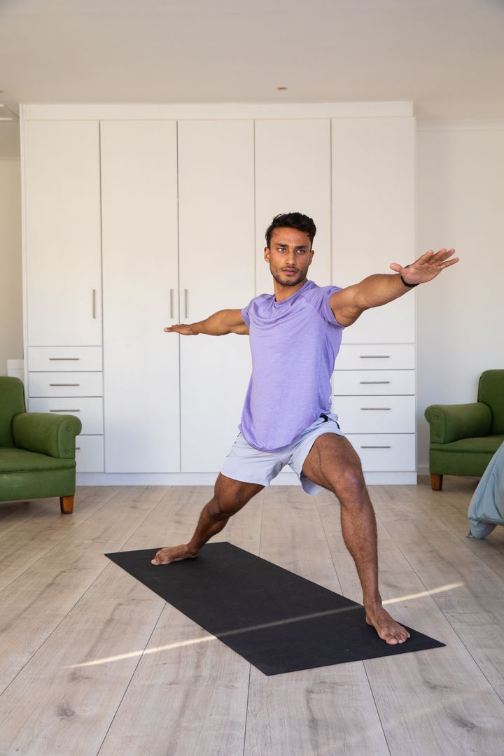 Man Practicing Warrior II Pose in Home Living Room