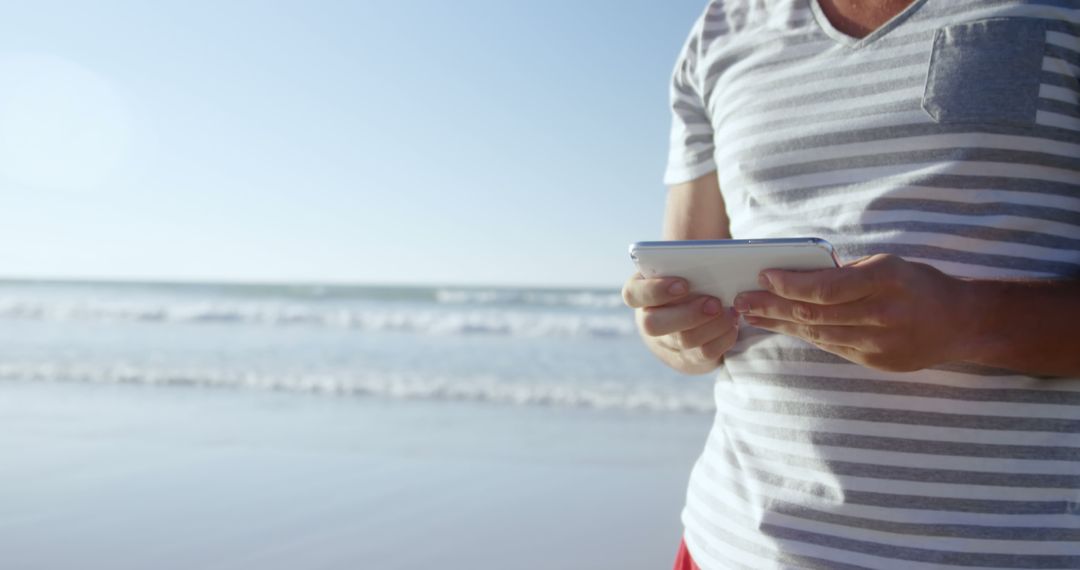 Man using tablet on sunny beach, technology vacation concept - Free Images, Stock Photos and Pictures on Pikwizard.com