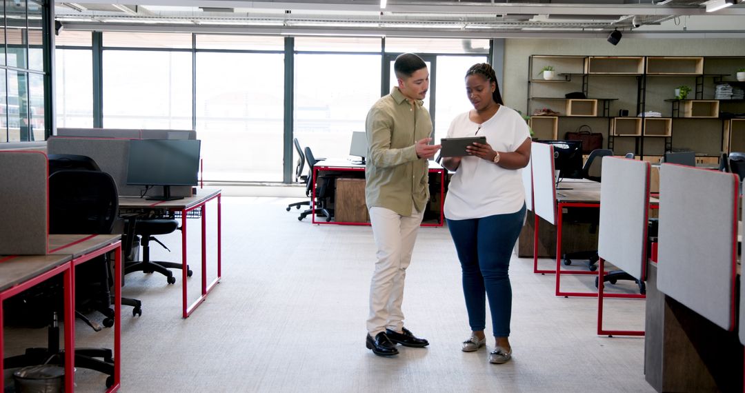 Colleagues Collaborating with Tablet in Modern Open-Plan Office
