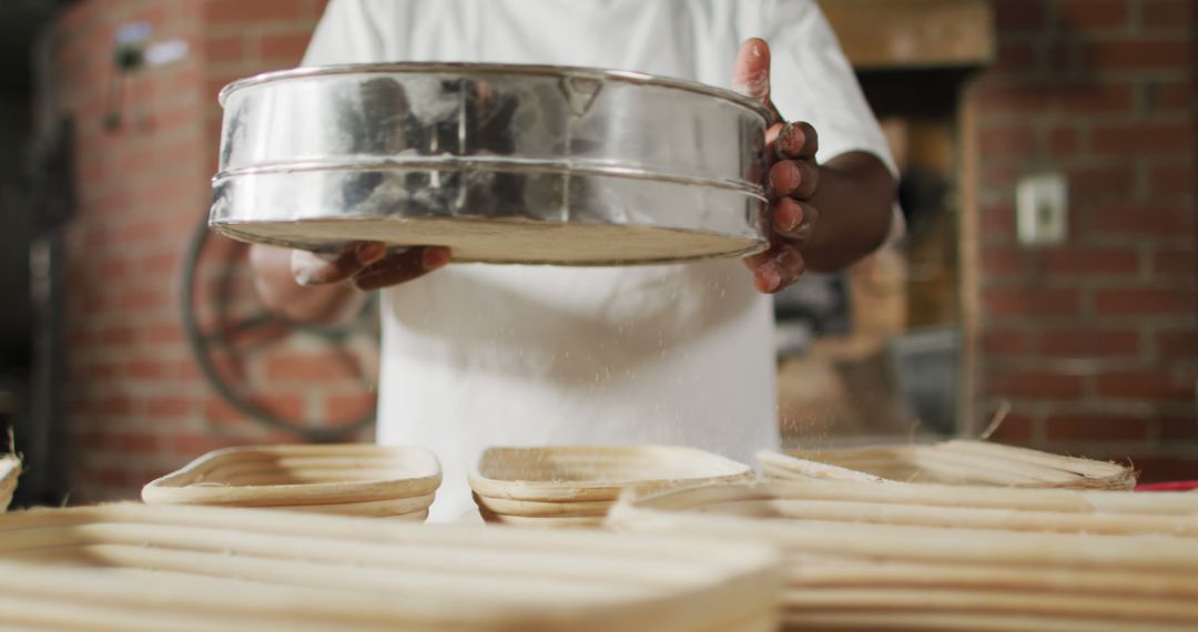 Baker sifting flour over bread molds in bakery workspace - Free Images, Stock Photos and Pictures on Pikwizard.com