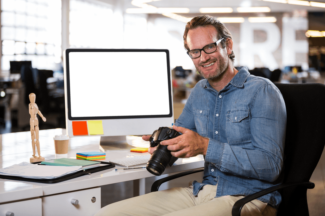 Man Holding Digital Camera at Office Desk in Transparent Workspace