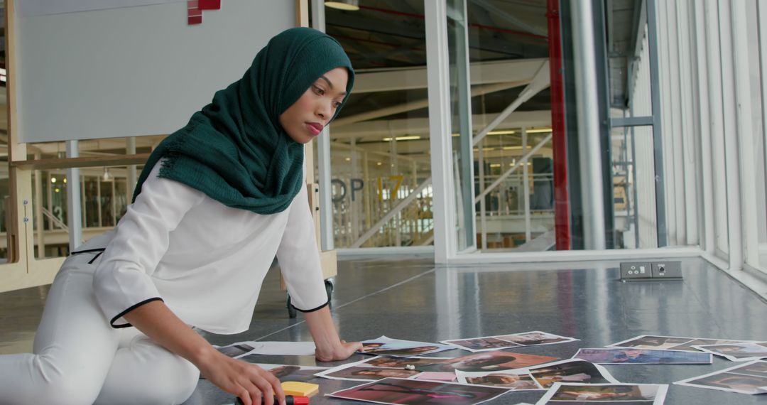 Muslim Woman Curating Photographs in Modern Office - Free Images, Stock Photos and Pictures on Pikwizard.com