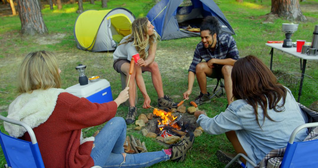 Friends Roasting Hotdogs Around Campfire in Forest Camping Scene - Free Images, Stock Photos and Pictures on Pikwizard.com