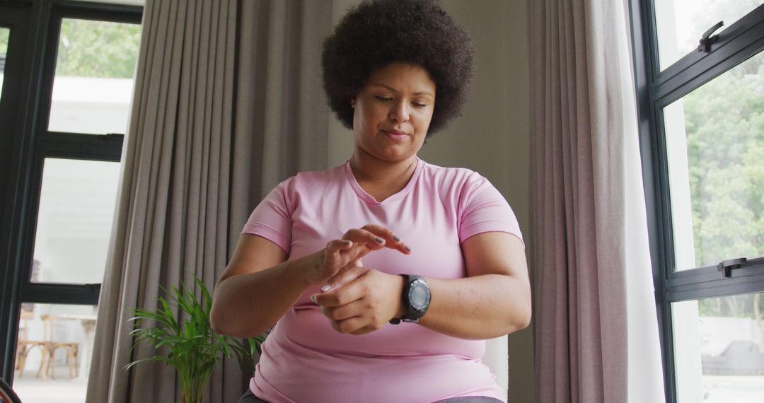 Image of plus size african american woman in sport clothes putting on smartwatch - Free Images, Stock Photos and Pictures on Pikwizard.com