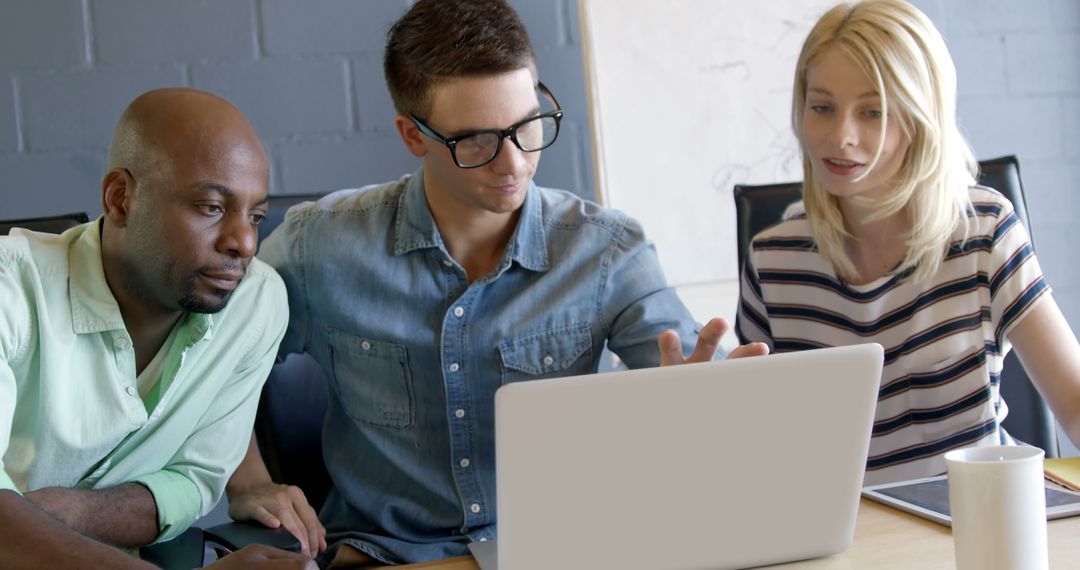 Diverse Professionals Collaborating Over Laptop in Office