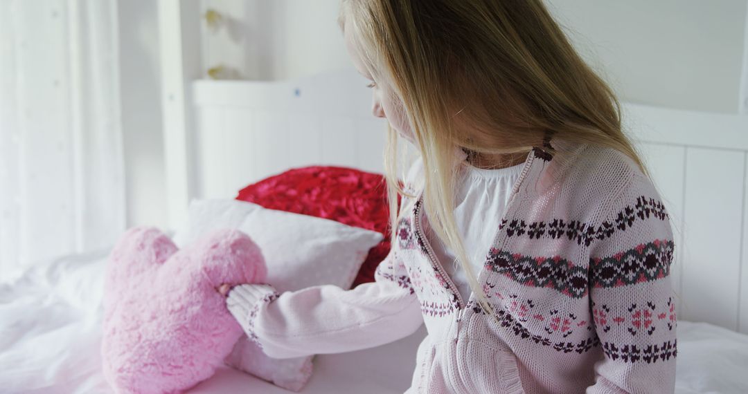 Young Girl Sitting on Bed Hugging Pink Heart-shaped Pillow - Free Images, Stock Photos and Pictures on Pikwizard.com