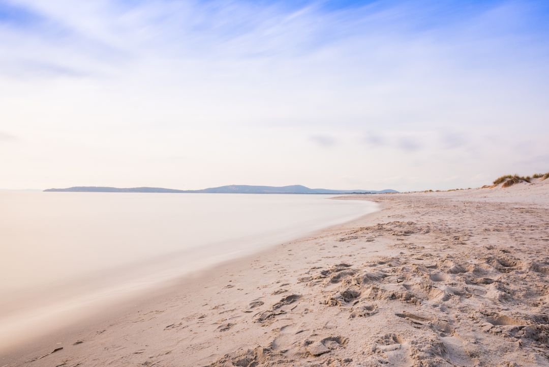 Serene Empty Sandy Beach with Smooth Water and Distant Islands at Soft Sunrise, Minimalist
