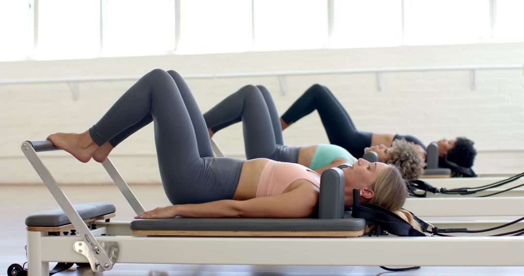Women Practicing On Pilates Reformers In Bright Studio