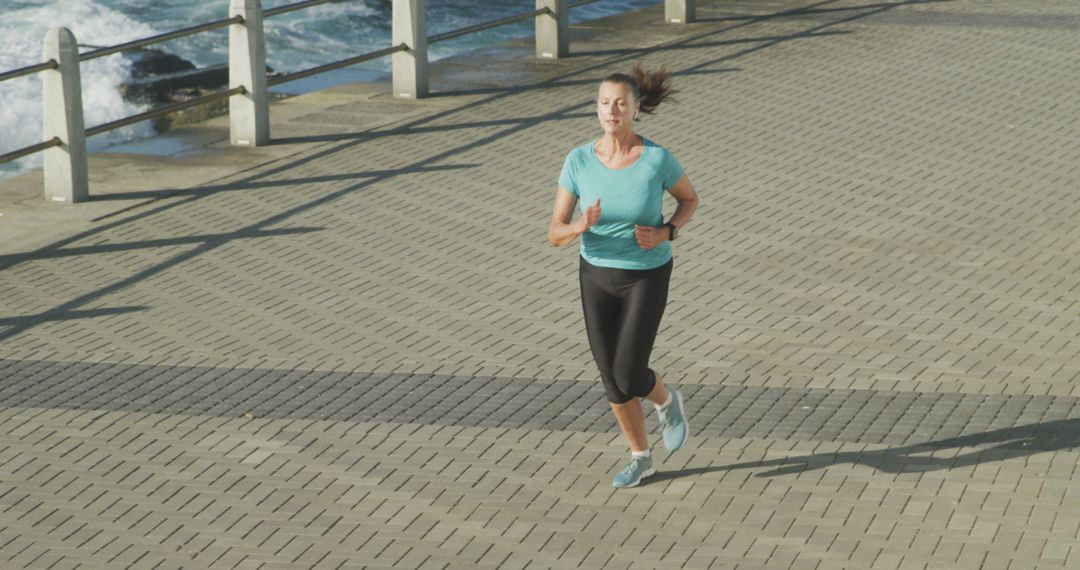 Woman jogging on waterfront path in sunny weather - Free Images, Stock Photos and Pictures on Pikwizard.com