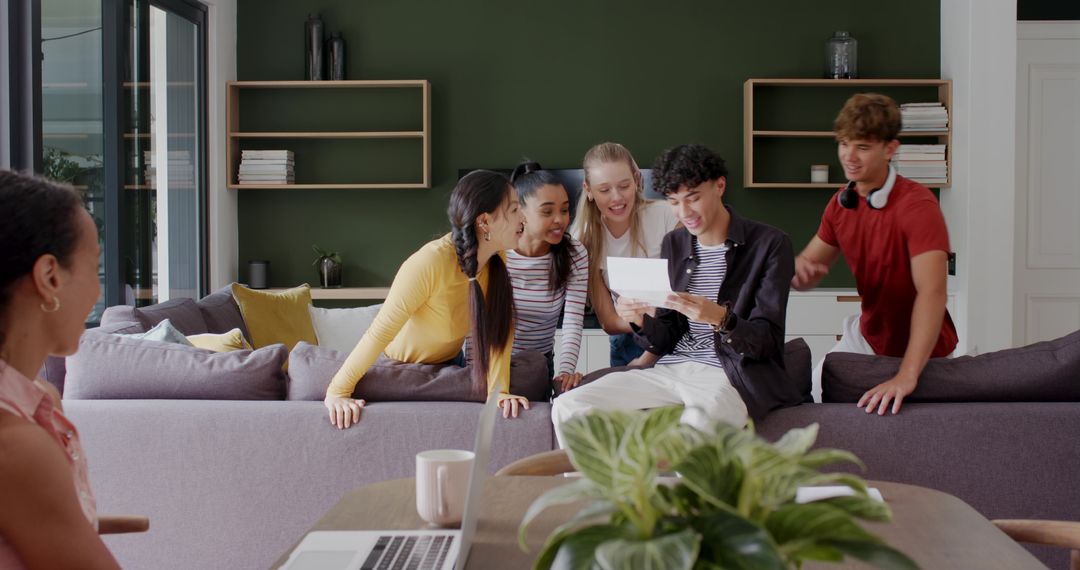 Diverse friends gathering around sofa, reading letter and celebrating in modern lounge