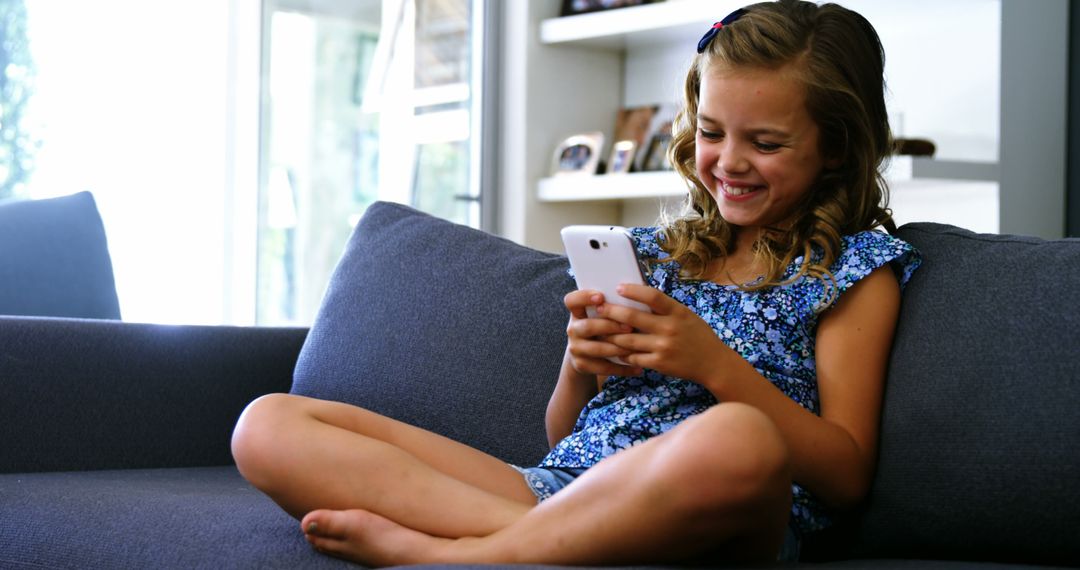 Happy Young Girl Using Smartphone Sitting on Sofa at Home - Free Images, Stock Photos and Pictures on Pikwizard.com