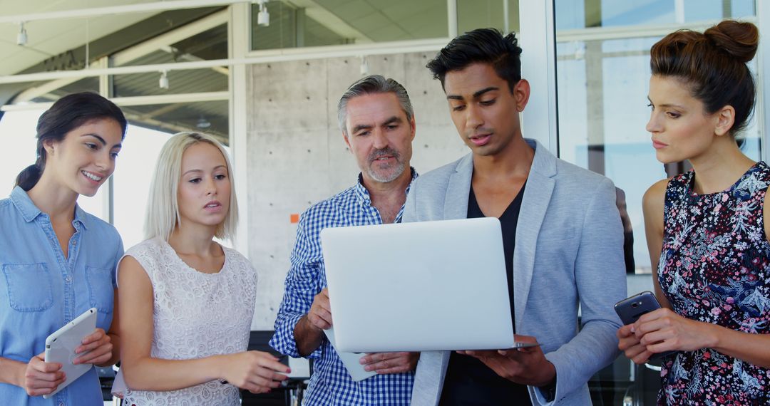 Focused Team Gathering Around Laptop in Office Environment