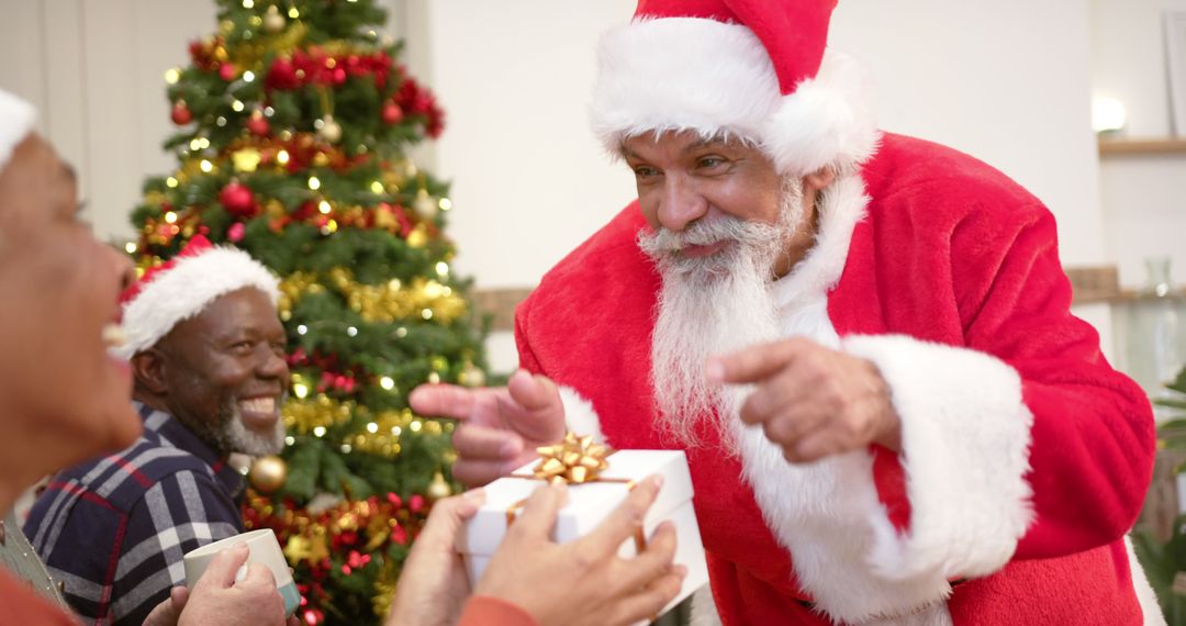 Santa Claus Giving Gift to Smiling Elderly Man by Christmas Tree - Free Images, Stock Photos and Pictures on Pikwizard.com