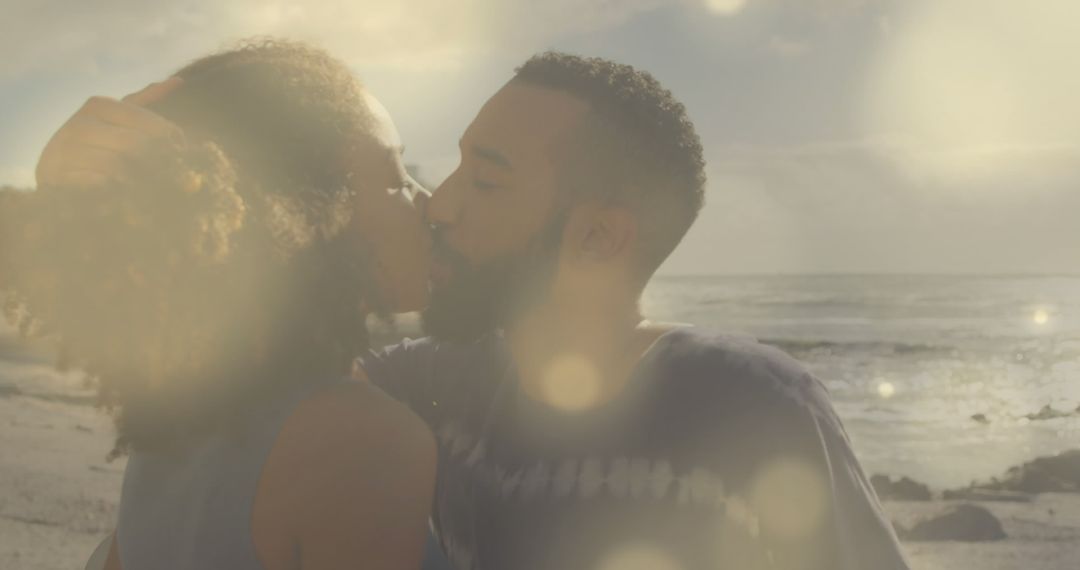 Image of lens flares over diverse couple embracing and kissing on beach against sea and sky - Free Images, Stock Photos and Pictures on Pikwizard.com