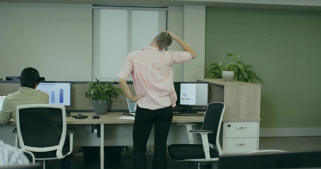 Female Office Worker in Pink Shirt Using Computers in Modern Workspace