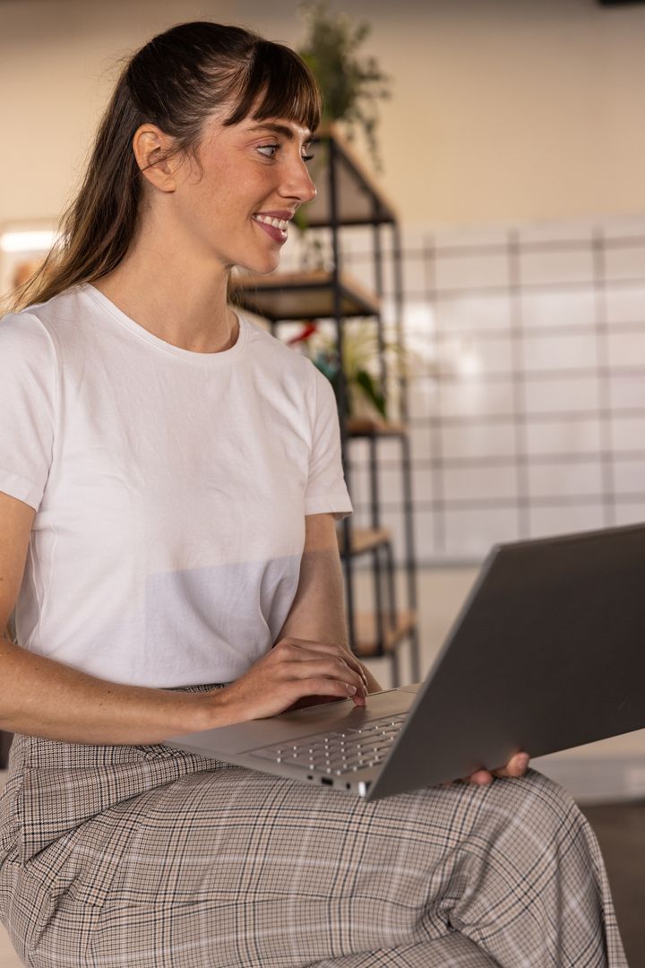 Smiling Woman Working on Laptop in Modern Home Office Setup