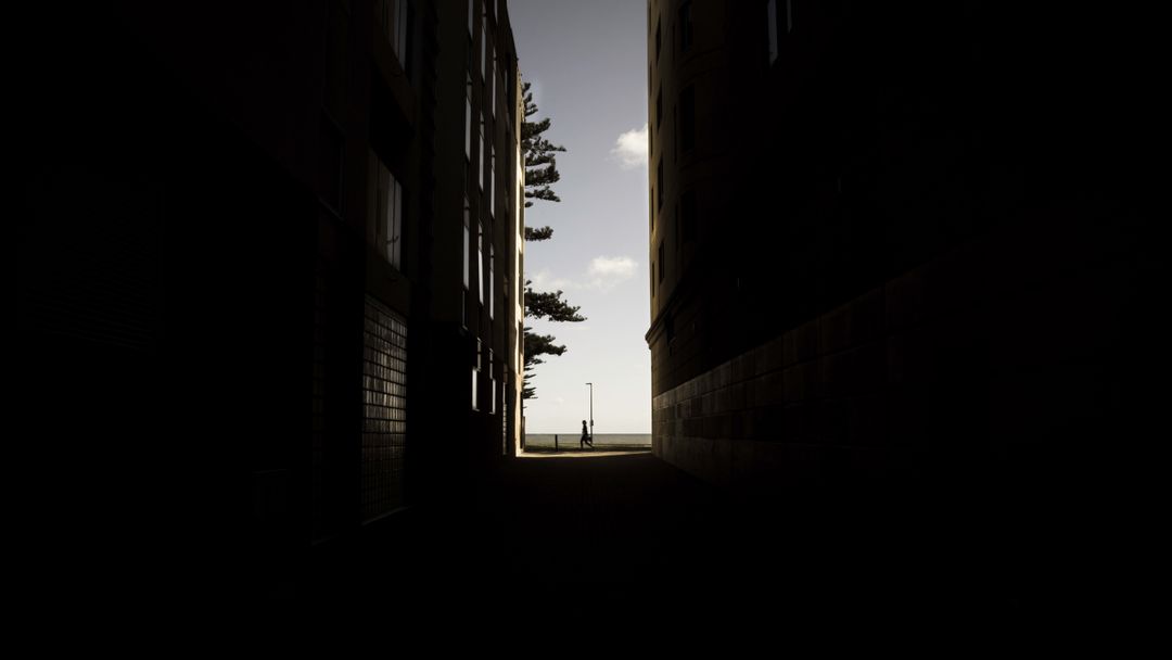 Person Standing at End of Dark Alley with Sunlit Entrance - Free Images, Stock Photos and Pictures on Pikwizard.com