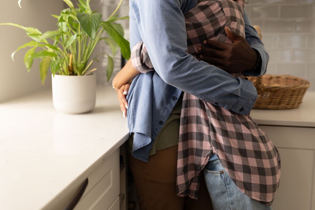 Midsection of african american young woman embracing boyfriend while standing by kitchen counter - Free Images, Stock Photos and Pictures on Pikwizard.com