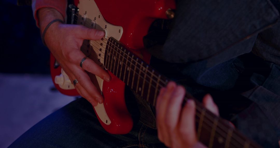 Close-Up of Hands Playing Red Electric Guitar in Studio Setting