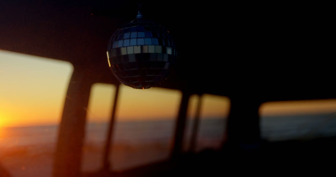 Sunset Beach View Through Van Windows with Hanging Disco Ball - Free Images, Stock Photos and Pictures on Pikwizard.com