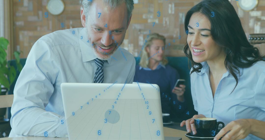 Colleagues Reviewing Laptop Over Coffee in Cafe Collaborating on Project and Brainstorming