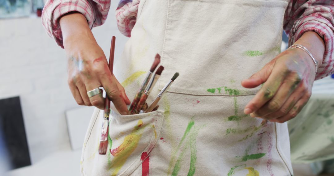 Abstract artist’s hands holding paintbrushes in apron pocket - Free Images, Stock Photos and Pictures on Pikwizard.com