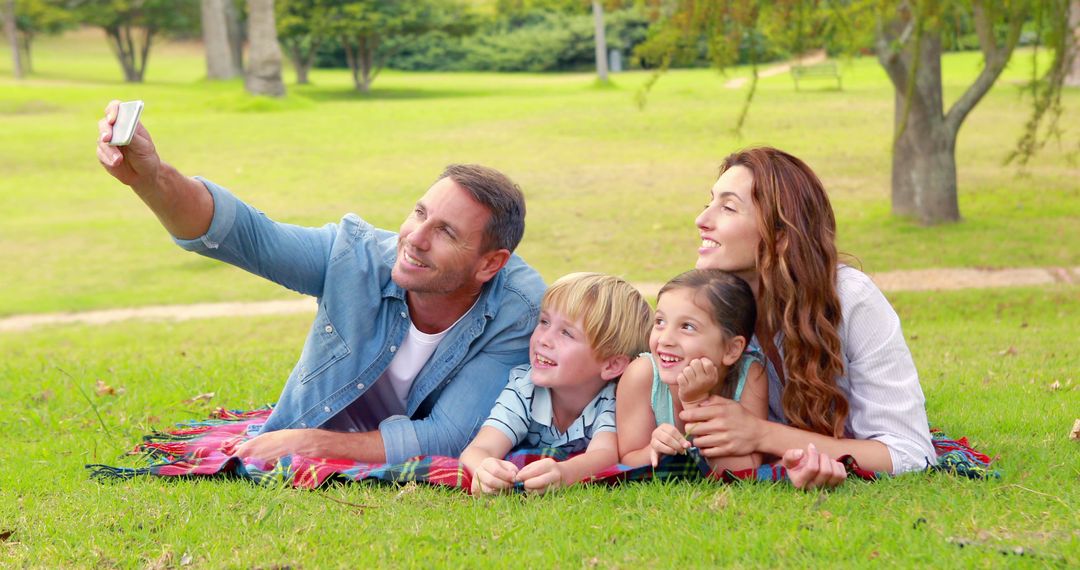 Happy Family Taking Selfie While Lying on Grass in Park - Free Images, Stock Photos and Pictures on Pikwizard.com