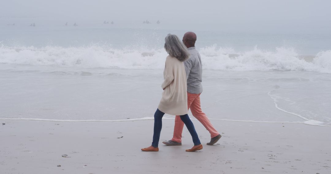 Senior Couple Walking on Beach in Overcast Weather - Free Images, Stock Photos and Pictures on Pikwizard.com