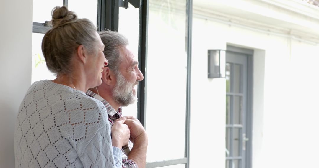 Senior Couple Embracing at Home Near Window with Lantern