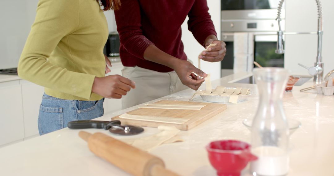 Diverse couple preparing pastry on bright modern kitchen island with rolling pin