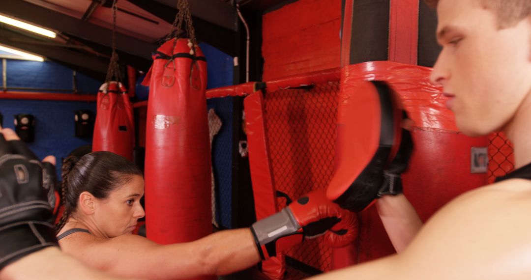 Focused Individuals Training with Punch Mitts at Boxing Gym - Free Images, Stock Photos and Pictures on Pikwizard.com