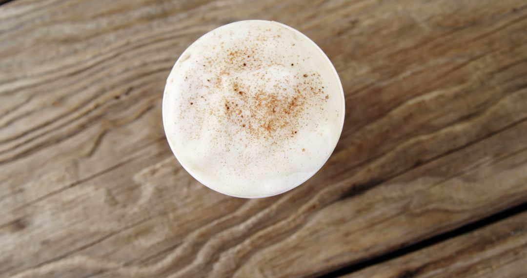 Overhead view of frothy cappuccino with cinnamon on rustic wooden table - Free Images, Stock Photos and Pictures on Pikwizard.com