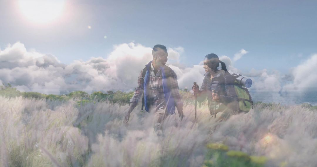 Couple Backpacking Through Sunny Hillside Meadow