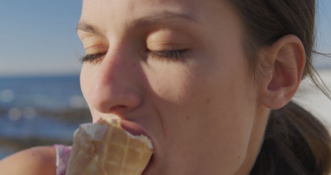 Happy caucasian woman eating ice cream at beach on sunny day - Free Images, Stock Photos and Pictures on Pikwizard.com