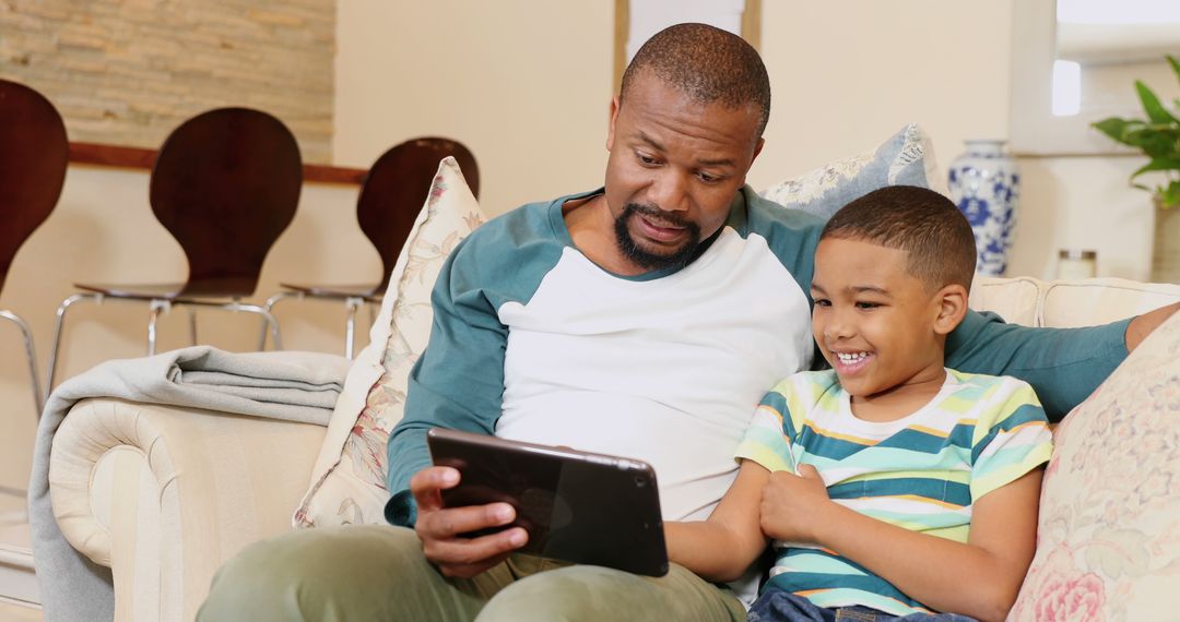 Father and Son Using Tablet Together on Couch - Free Images, Stock Photos and Pictures on Pikwizard.com