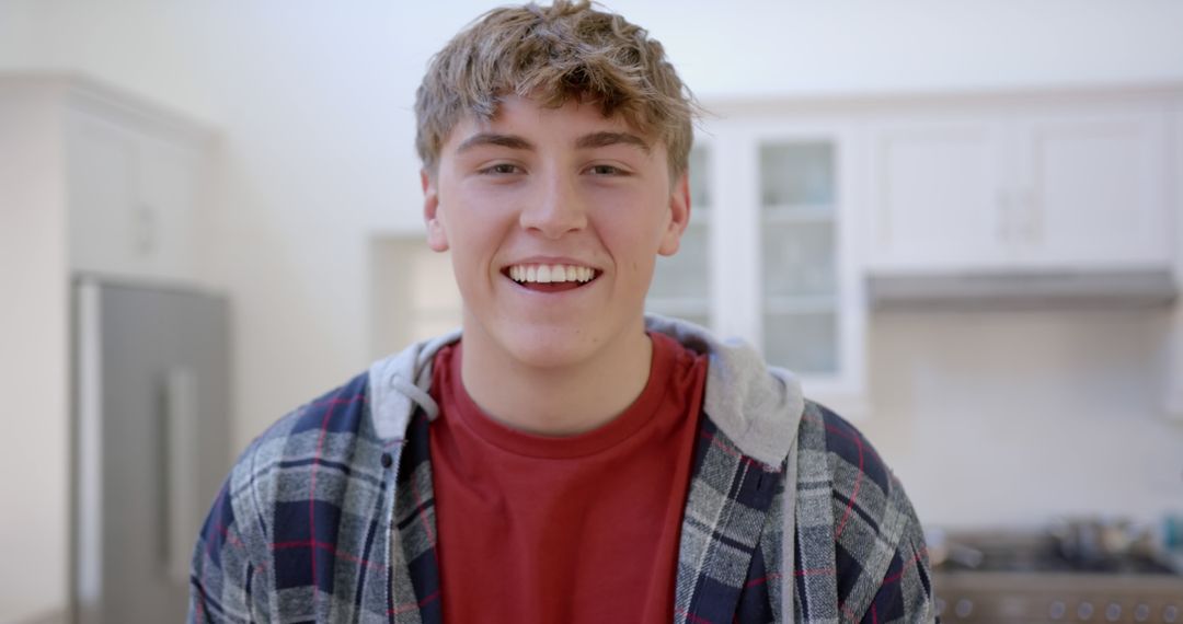 Young Man Smiling in Kitchen Wearing Plaid Shirt - Free Images, Stock Photos and Pictures on Pikwizard.com