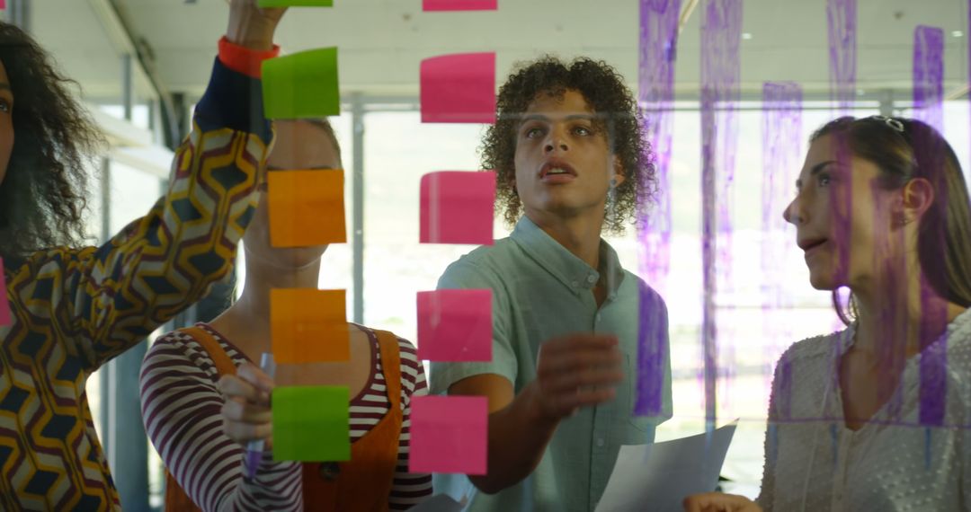 Team Collaboration with Sticky Notes on Glass Wall in Modern Office