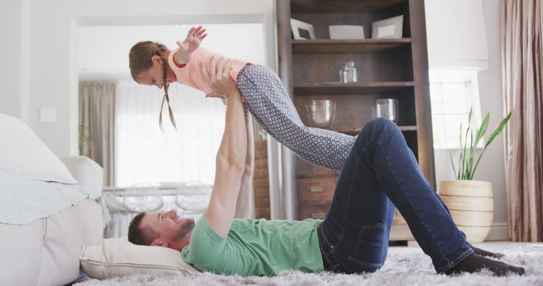 Father playing with daughter lifting her in air at home - Free Images, Stock Photos and Pictures on Pikwizard.com