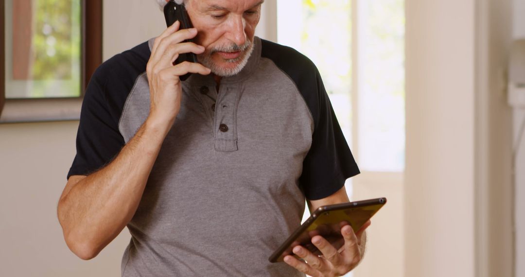 Senior man talking on phone while using tablet at home - Free Images, Stock Photos and Pictures on Pikwizard.com