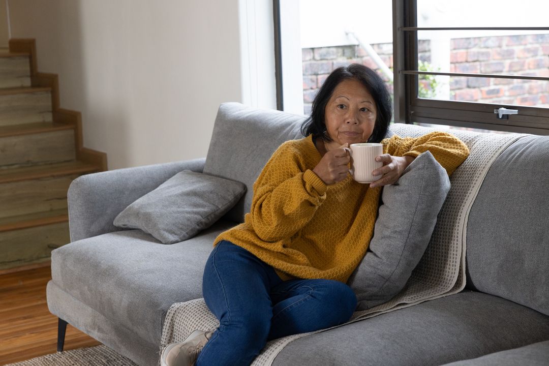 Senior Woman Relaxing on Cozy Couch with Coffee Mug